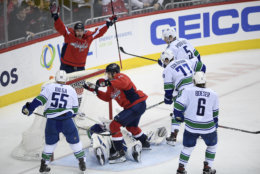 Washington Capitals right wing Brett Connolly (10) scores a goal against Vancouver Canucks goaltender Jacob Markstrom, laying on ice, defenseman Alex Biega (55), right wing Brock Boeser (6), right wing Nikolay Goldobin (77) and defenseman Derrick Pouliot (5) during the third period of an NHL hockey game, Tuesday, Feb. 5, 2019, in Washington. Also seen is Capitals left wing Jakub Vrana, top. The Capitals won 3-2. (AP Photo/Nick Wass)