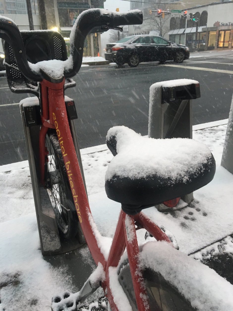 A cold, and wet ride: Snow gathers on a Capital Bikeshare seat in Friendship Heights on Wednesday morning. (WTOP/Sarah Beth Hensley)