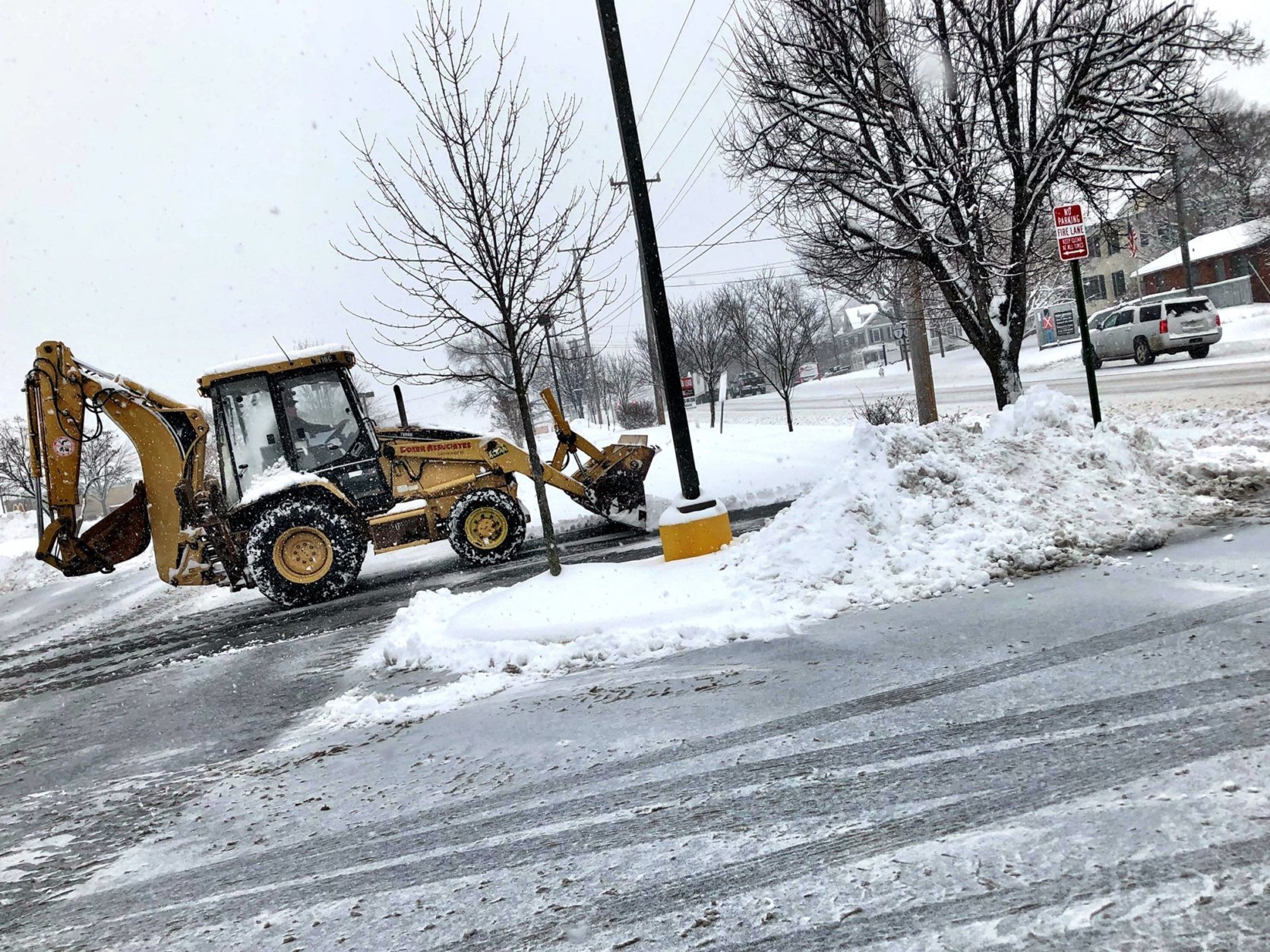 A backhoe begins the messy task of cleaning up the snow in Purcellville. (WTOP/Neal Augenstein)