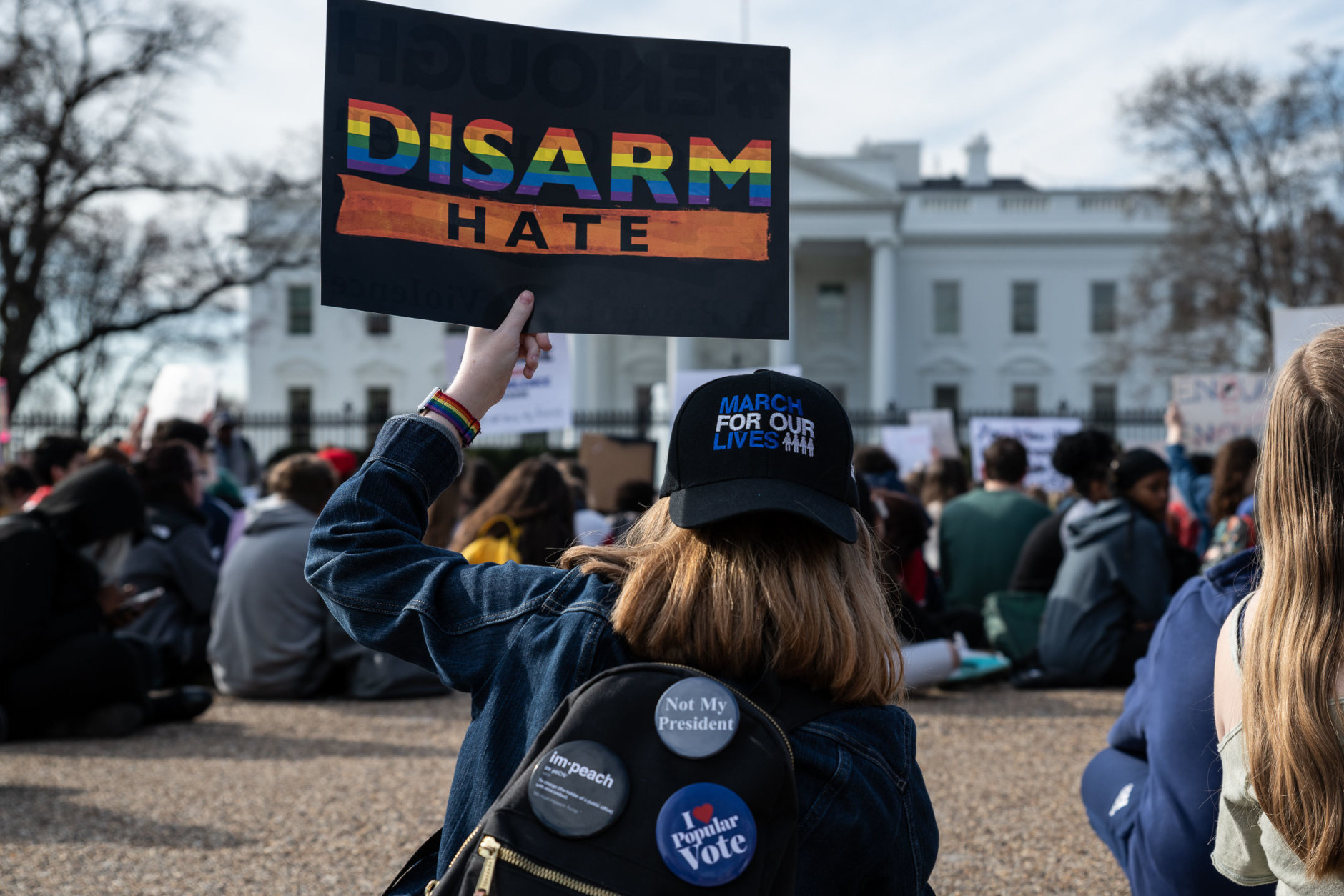 A student with a March for Our Lives hat sits outside the White House during a walkout for gun control from area schools on March 14 — almost one year since hundreds of thousands filled the streets of D.C. in a protest against gun violence. (WTOP/Alejandro Alvarez)