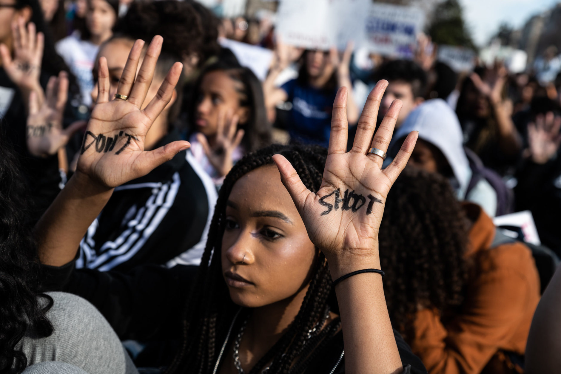 A protester sits with her hands facing the White House during a moment of silence at the student walkout against gun violence on March 14, 2019. (WTOP/Alejandro Alvarez)