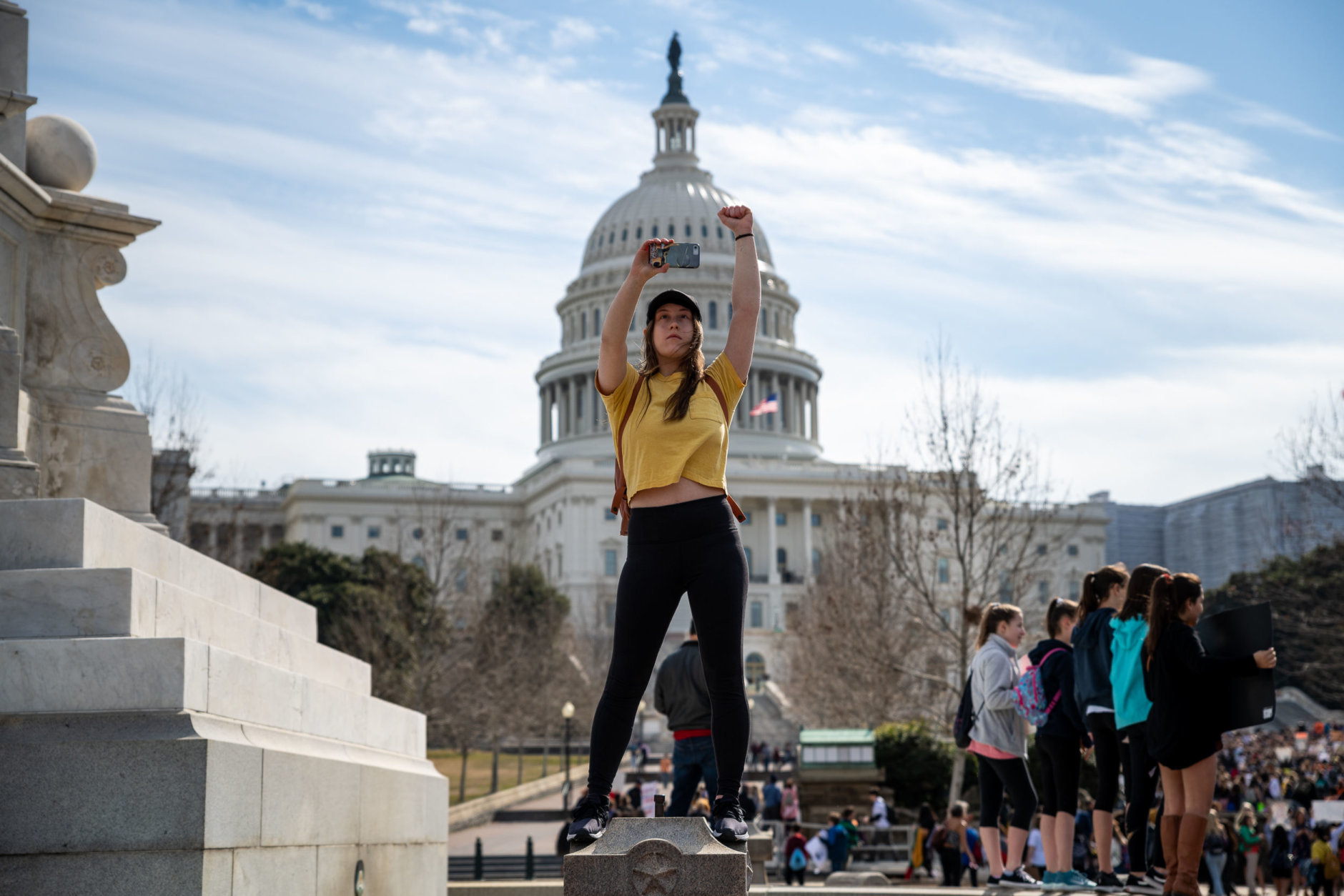 A protester holds her fist up, welcoming hundreds of students to the rally site on the Capitol building's west lawn. Here, protesters heard from both activists and members of Congress whose constituents have been directly impacted by shootings like Sandy Hook. (WTOP/Alejandro Alvarez)