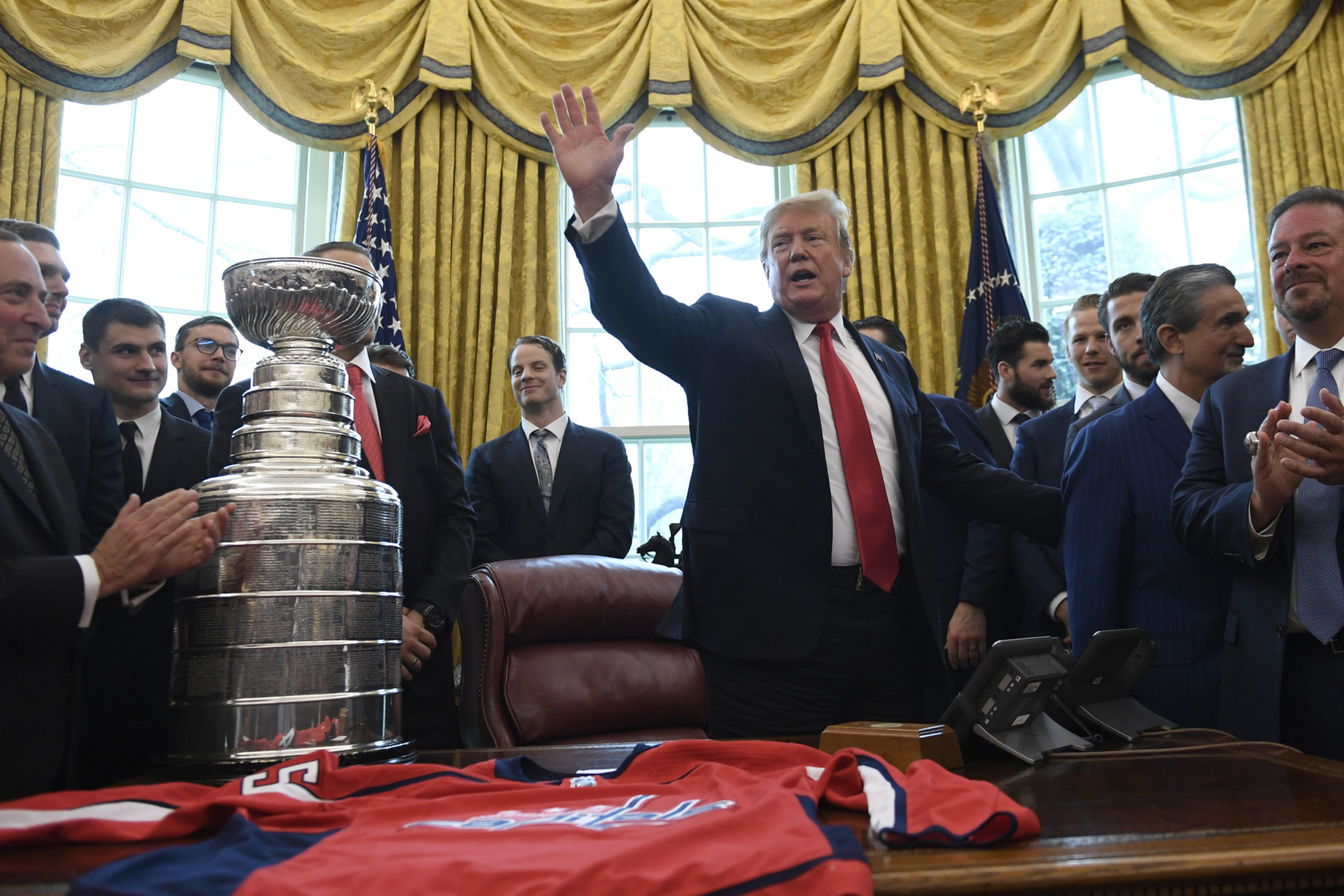 President Donald Trump, center, waves after hosting the 2018 Stanley Cup Champion Washington Capitals hockey team in the Oval Office of the White House in Washington, Monday, March 25, 2019. (AP Photo/Susan Walsh)