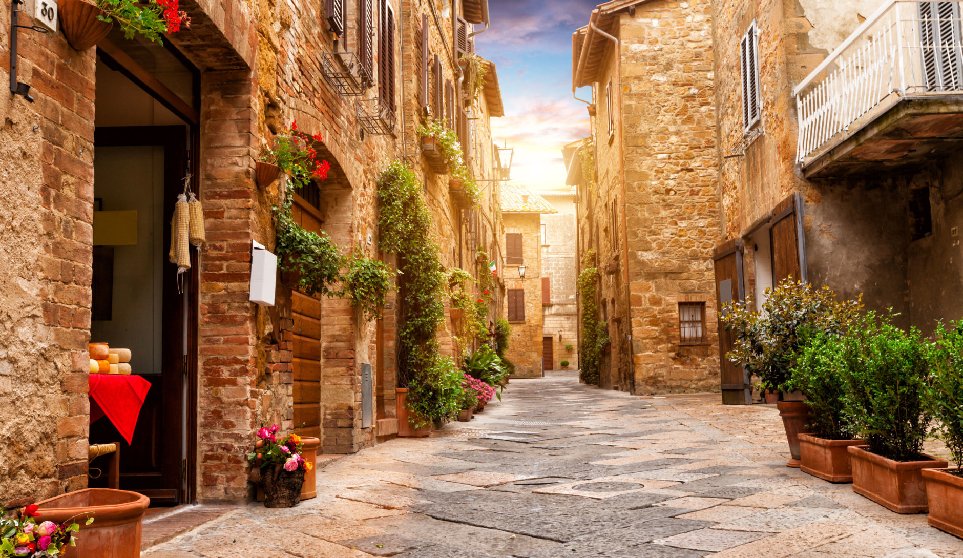Colorful street in Pienza with many decoration flowers and trees, Tuscany, Italy