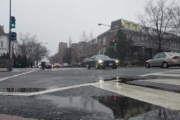 Snow falls on wet roads in Columbia Heights, D.C. (WTOP/Will Vitka)