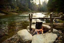 Cooking on bonfire. Campfire near mountain river. Camping fire on the river bank. 
