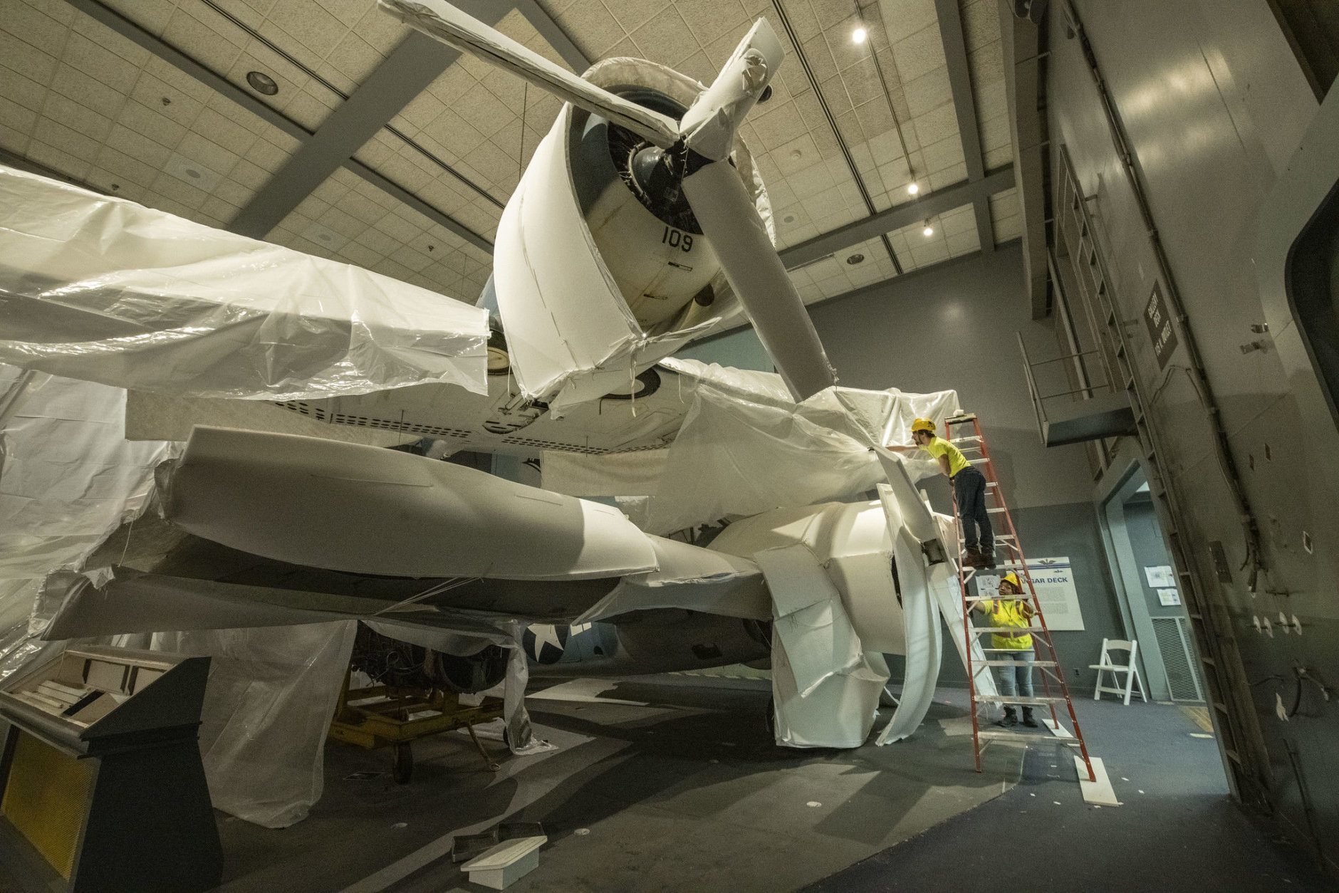 Contractors from Crozier Fine Arts work to protect in place the Hellcat aircraft in the closed Sea-Air Operations gallery as part of the renovation underway at the National Air and Space Museum in Washington, DC, February 19, 2019. (Smithsonian photo by Jim Preston)  Material is subject to Smithsonian Terms of Use. Should you wish to use National Air and Space material in any medium, please submit an Application for Permission to Reproduce NASM Material, available at:  https://airandspace.si.edu/permissions