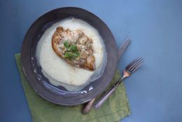 This December 2017 photo shows grits with chicken and tomatillo green chili and sour cream pan sauce in New York. This dish is from a recipe by Katie Workman. (Lucy Beni via AP)