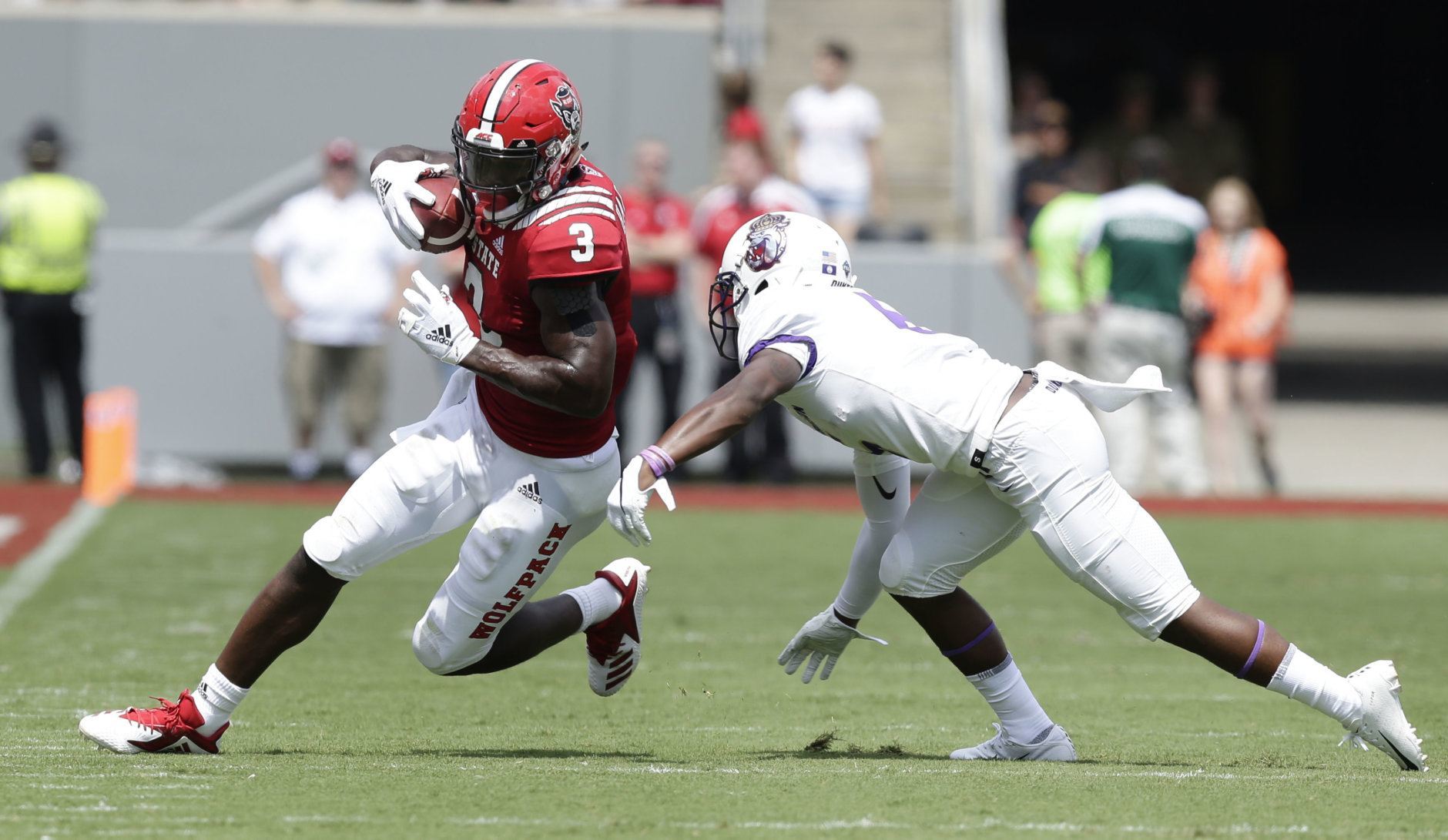 North Carolina State's Kelvin Harmon (3) runs the ball while James Madison's Jimmy Moreland dives for the tackle during the first half an NCAA college football game in Raleigh, N.C., Saturday, Sept. 1, 2018. (AP Photo/Gerry Broome)