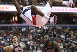 Washington Wizards center Thomas Bryant, top, changes on the rim after he dunked against Chicago Bulls guard Ryan Arcidiacono (51) and forward JaKarr Sampson (41) during the second half of an NBA basketball game, Wednesday, April 3, 2019, in Washington. The Bulls won 115-114. (AP Photo/Nick Wass)