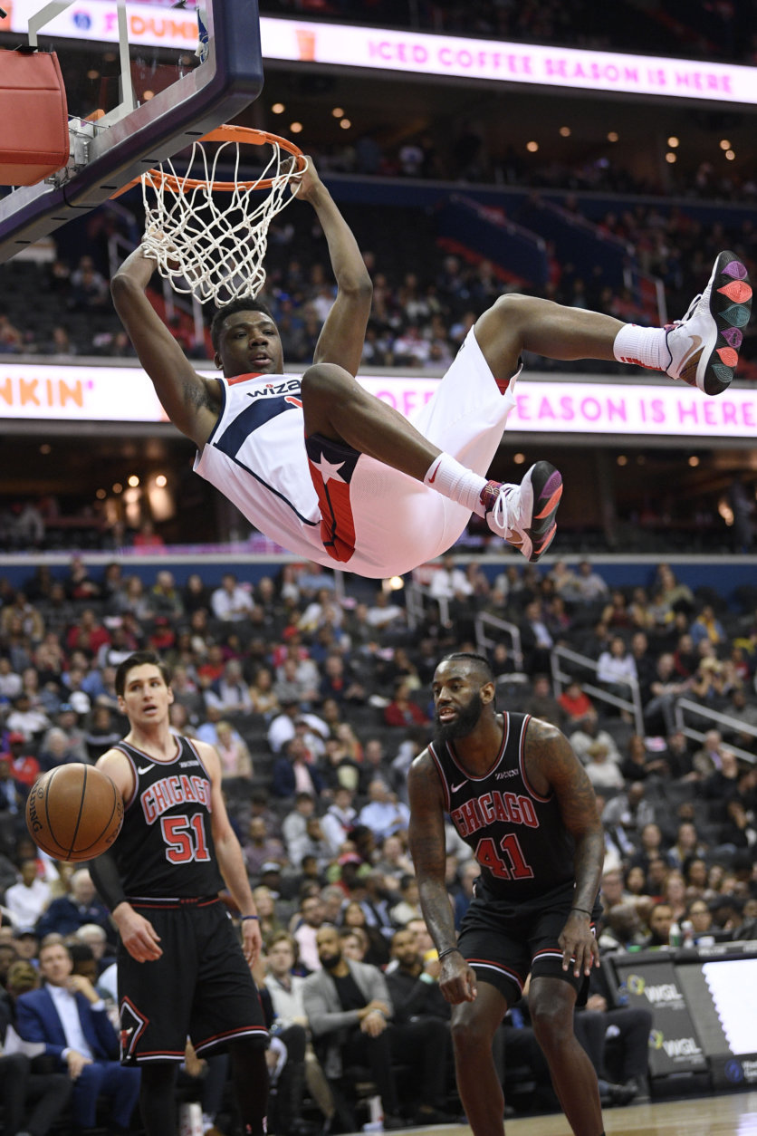 Washington Wizards center Thomas Bryant, top, changes on the rim after he dunked against Chicago Bulls guard Ryan Arcidiacono (51) and forward JaKarr Sampson (41) during the second half of an NBA basketball game, Wednesday, April 3, 2019, in Washington. The Bulls won 115-114. (AP Photo/Nick Wass)