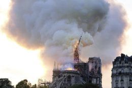 Flames and smoke rise as the spire on Notre Dame cathedral collapses in Paris, Monday, April 15, 2019. Massive plumes of yellow brown smoke is filling the air above Notre Dame Cathedral and ash is falling on tourists and others around the island that marks the center of Paris. (AP Photo/Diana Ayanna)