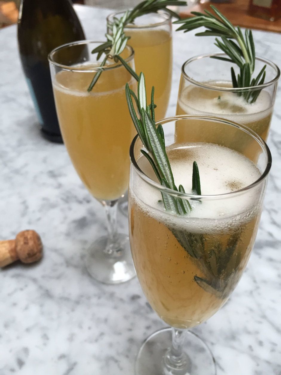 This Dec. 3, 2015, photo, shows sparkling orchard grove cocktails, which spike sparkling wine with an apple cider-orange juice reduction, amaretto liqueur and a sprig of fresh rosemary in Concord, N.H. The New Years Eve cocktail can be prepared ahead of time. (AP Photo/J.M. Hirsch)