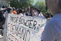 Activists hold a sign calling on the Bowser administration to create safer roads in D.C. after a biker was killed on Florida Avenue in Northeast D.C. (WTOP/Melissa Howell)