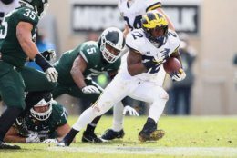 EAST LANSING, MI - OCTOBER 20: Karan Higdon #22 of the Michigan Wolverines escapes the tackle of Andrew Dowell #5 of the Michigan State Spartans during a second quarter run at Spartan Stadium on October 20, 2018 in East Lansing, Michigan. (Photo by Gregory Shamus/Getty Images)