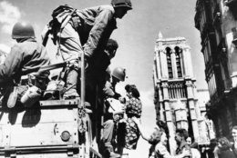 United States soldiers are shown being joyfully greeted by French women in the shadow of Notre Dame Cathedral in Paris, August 28, 1944. They dance and one girl seems to be pulling a soldier from the truck. (AP Photo)