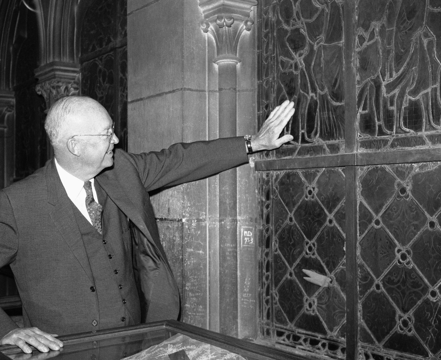 President Dwight Eisenhower runs his hand over surface of one of the stained glass windows in Cathedral of Notre Dame, May 18, 1960 as he toured churches din the French Capital. (AP Photo)