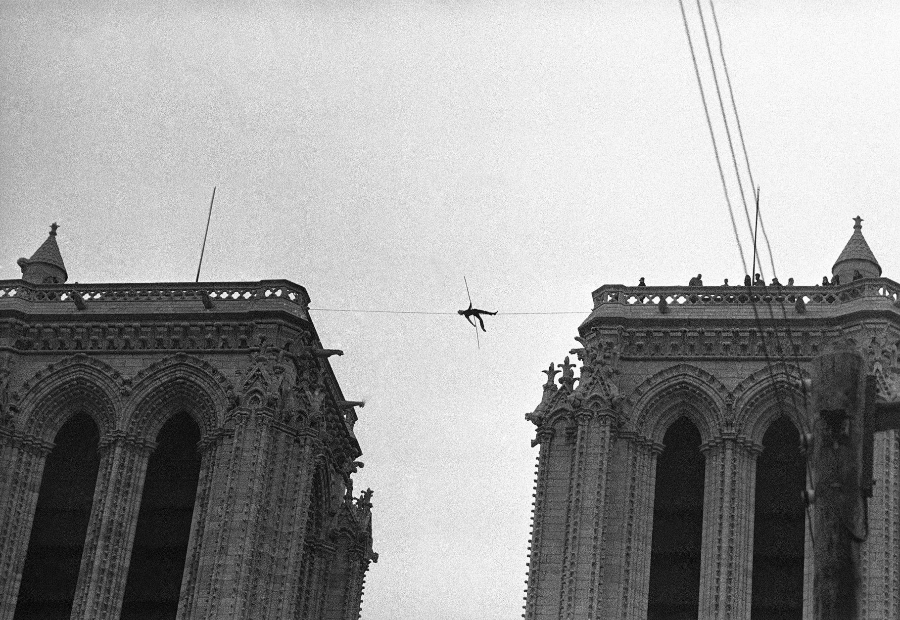 Philippe Petit, a 21-year-old professional tightrope walker, appears as the tiny figure as he lies on a tightrope, strung 225 feet above the ground, between the two towers of Notre Dame Cathedral, Paris, France on June 26, 1971, during a stunt which lasted several hours, with police unable to bring him down. (AP Photo/Str/Cardenas)
