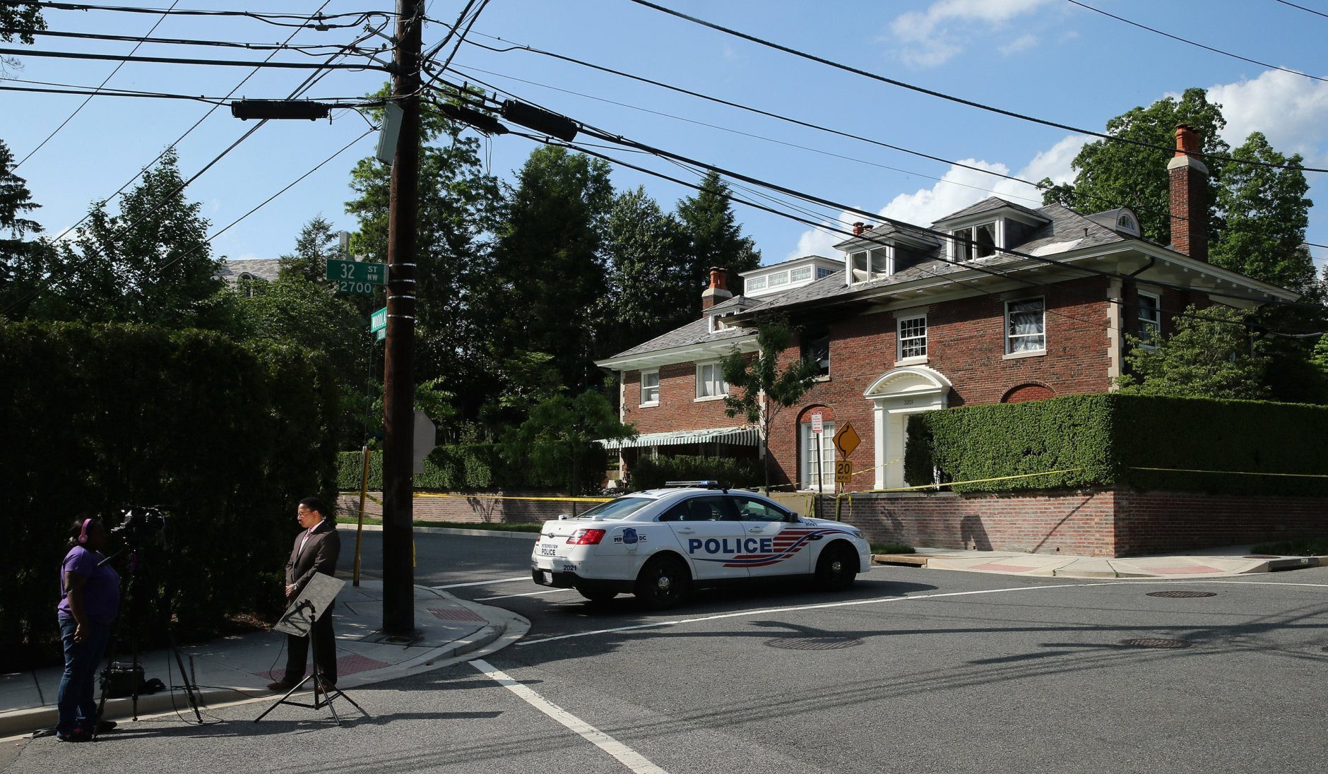 WASHINGTON, DC - MAY 19:  A television reporter waits to go live across the street from a house on the 3200 block of Woodland Drive NW May 19, 2015 in Washington, DC. Firefighters discovered the bodies of Savvas Savopoulos, 46, his wife Amy, 47, their 10-year-old son Philip, and the housekeeper, Veralicia Figueroa, 57, last Thursday afternoon when they responded to a blaze at the house. Two Savopoulos daughters were away in boarding school at the time. Investigators have ruled the deaths homicides and say they could continue to collect evidence at the house for another week.  (Photo by Chip Somodevilla/Getty Images)