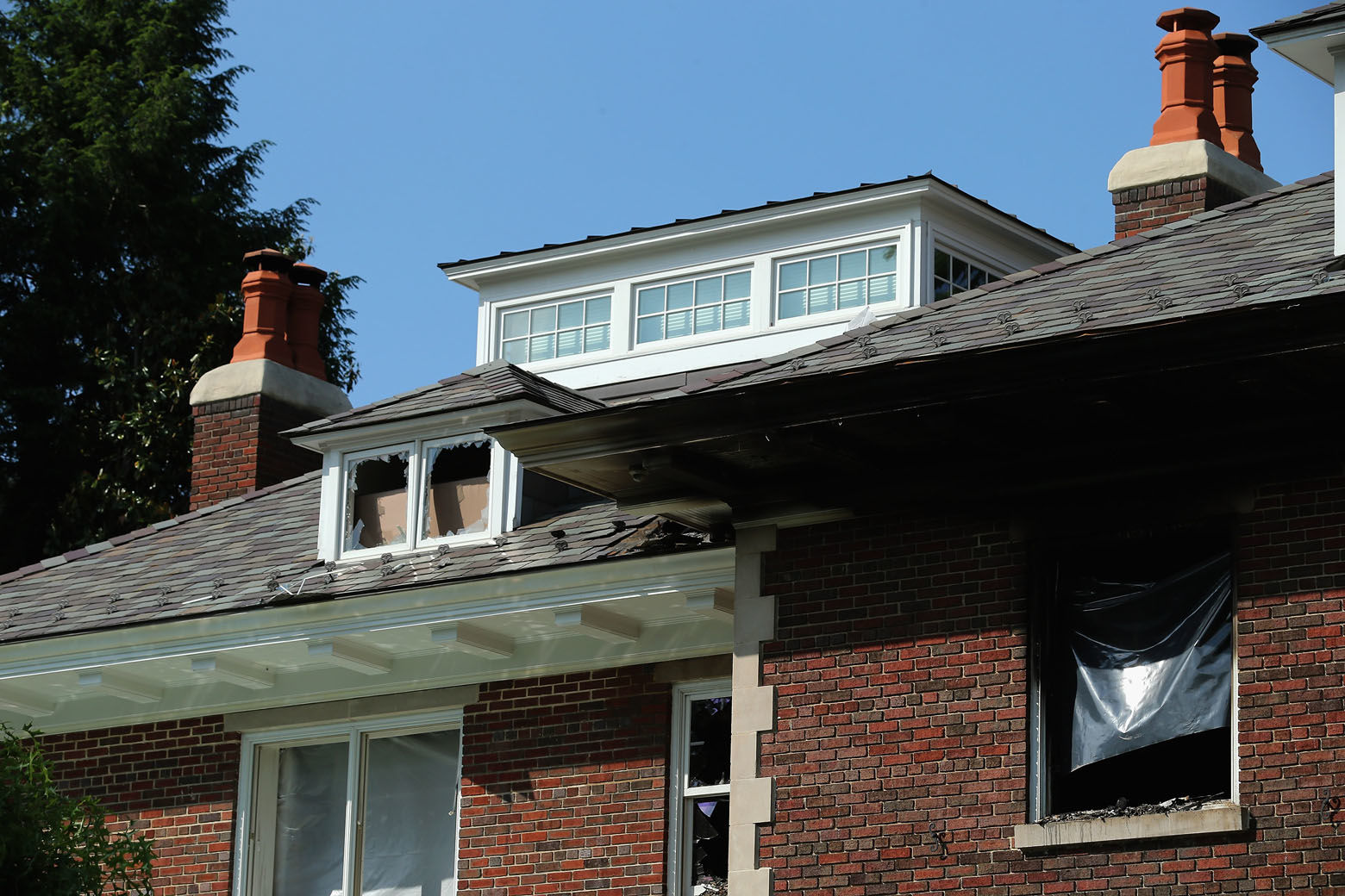 WASHINGTON, DC - MAY 19:  Smashed windows and heavy fire damage scar a house on the 3200 block of Woodland Drive NW May 19, 2015 in Washington, DC. Firefighters discovered the bodies of Savvas Savopoulos, 46, his wife Amy, 47, their 10-year-old son Philip, and the housekeeper, Veralicia Figueroa, 57, last Thursday afternoon when they responded to a blaze at the house. Two Savopoulos daughters were away in boarding school at the time. Investigators have ruled the deaths homicides and say they could continue to collect evidence at the house for another week.  (Photo by Chip Somodevilla/Getty Images)
