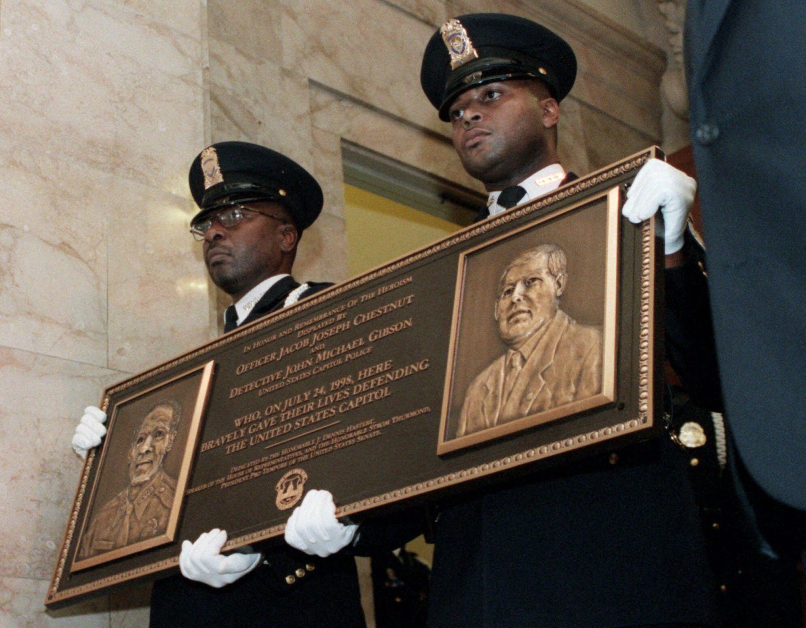 FILE — Capitol Hill officers carry a plaque on Capitol Hill Thursday, July 22, 1999 honoring slain officers Jacob Chestnut and John Gibson. (AP Photo/George Bridges, File)