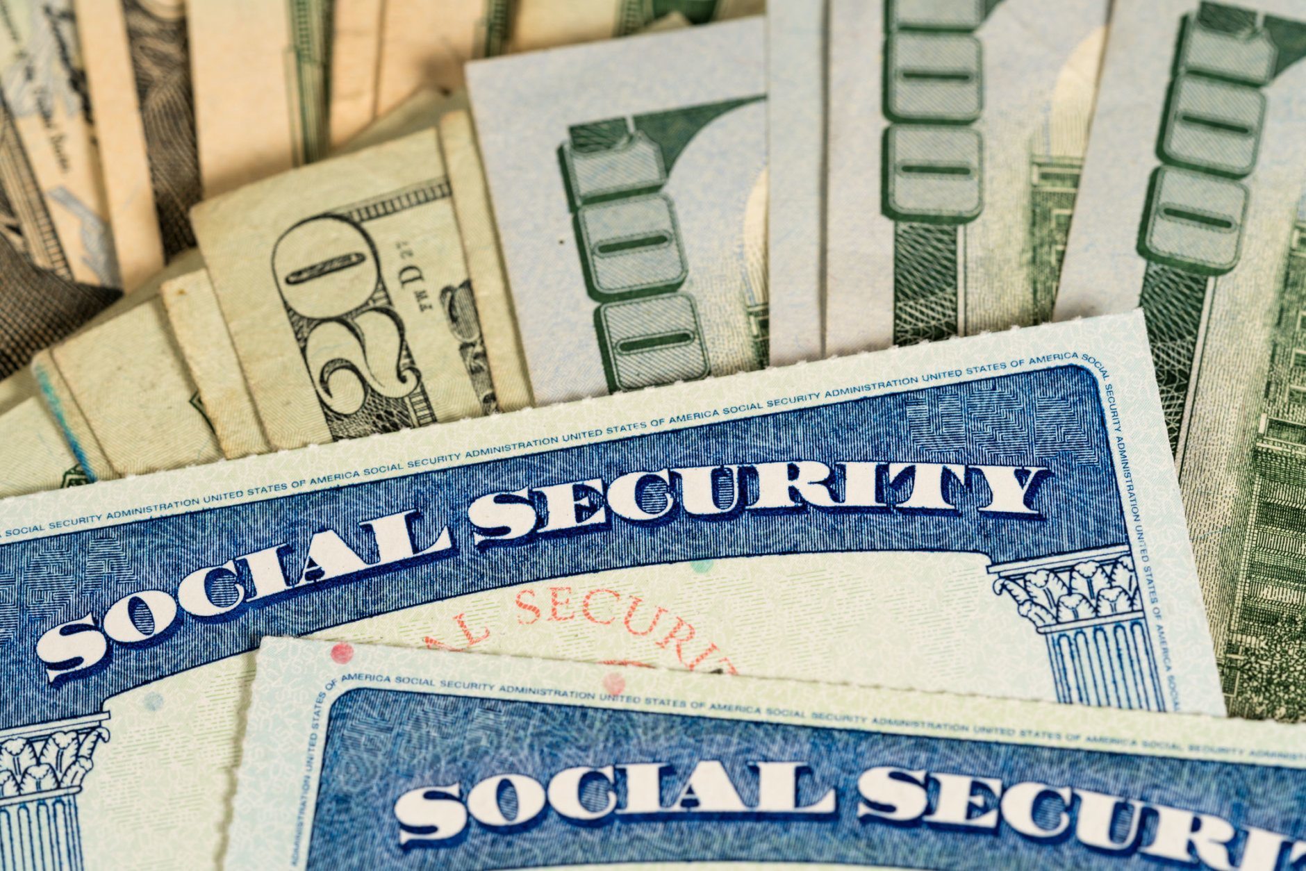 USA Social security cards laid on pile of dollar bills to illustrate money in retirement