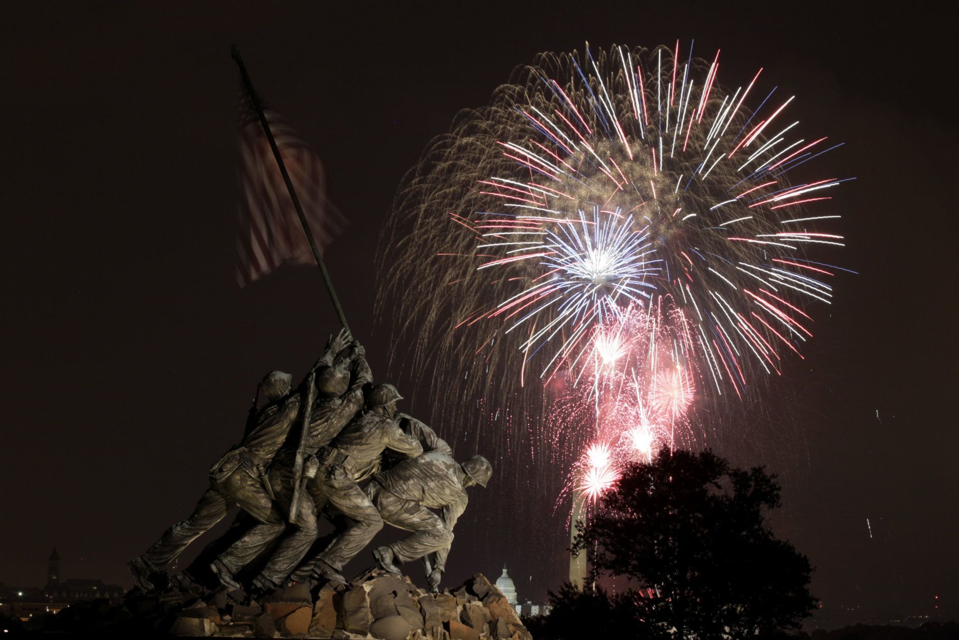 The United States Marine Corps War Memorial, better known as the Iwo Jima Memorial, is seen in Arlington, Va., Monday July 4, 2011, as fireworks burst over Washington, during the annual Fourth of July display. The Washington Monument and the Capitol can be seen in the distance. (AP Photo/Carolyn Kaster)