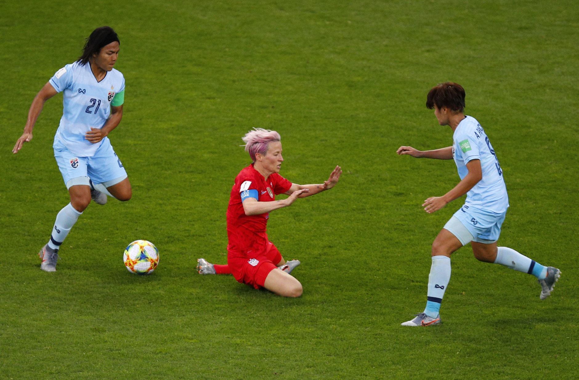 United States' Megan Rapinoe, centre, falls as Thailand's Kanjana Sung-Ngoen, left, and Ainon Phancha chase the gal during the Women's World Cup Group F soccer match between the United States and Thailand at the Stade Auguste-Delaune in Reims, France, Tuesday, June 11, 2019. (AP Photo/Francois Mori)