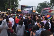 a crowd shields itself from the rain while gazing towards the stage at the Capital Pride Concert in 2019.