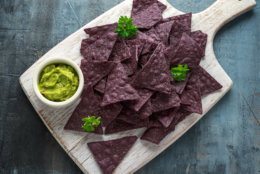 Blue corn Organic tortilla chips with Guacamole on white wooden board.