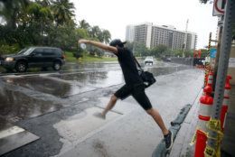 Ward Kea, of Honolulu, jumps over a puddle as he prepares to board a bus in Honolulu Sunday, Oct. 19, 2014. Hurricane Ana brought a steady rain to the Hawaiian Island of Oahu as it passed about 180 miles west. (AP Photo/P. Solomon Banda)