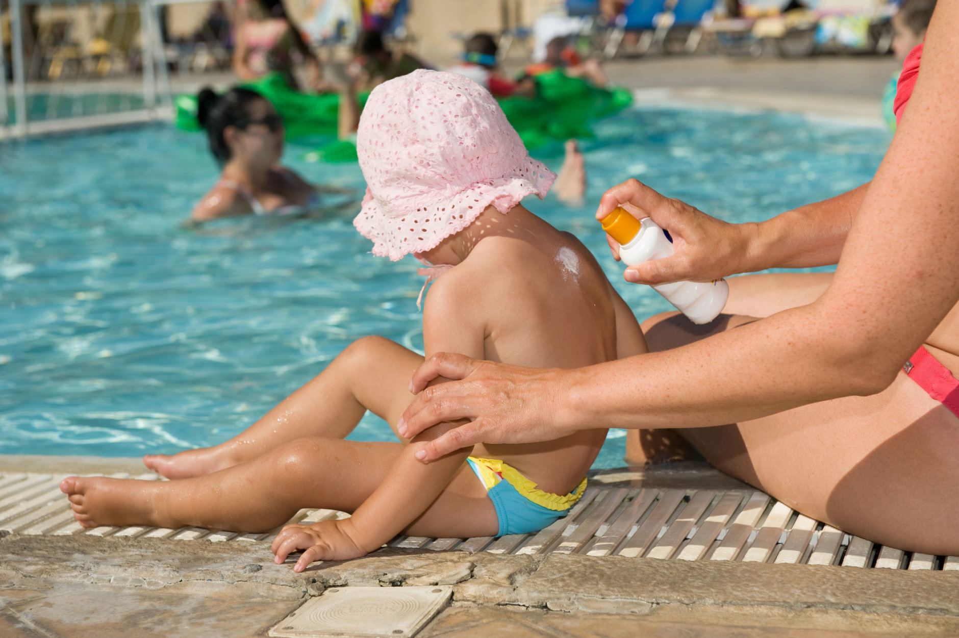 Mother applying baby suncream on the pool in summer