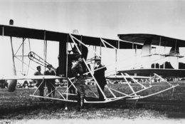 The U.S. president and some 7,000 spectators have gathered to watch the Wright brothers demonstrate their military flyer for the second time to the U.S. Army at Fort Myer, Va., on July 30, 1909.  Orville Wright took First Lt. Benjamin D. Foulois as observer on a 10-mile cross country flight to Shuter's Hill, Alexandria, Va., and back, completing all the terms of the sale for the world's first military plane.  The Wright brothers were paid the contract price of $25,000 and a $5,000 bonus for exceeding the required speed.  Standing near the propellers are Lt. Foulois, left, and Wilbur Wright.  At the tail end are Lt. Frank P. Lahm, left, and Orville Wright.  (AP Photo)