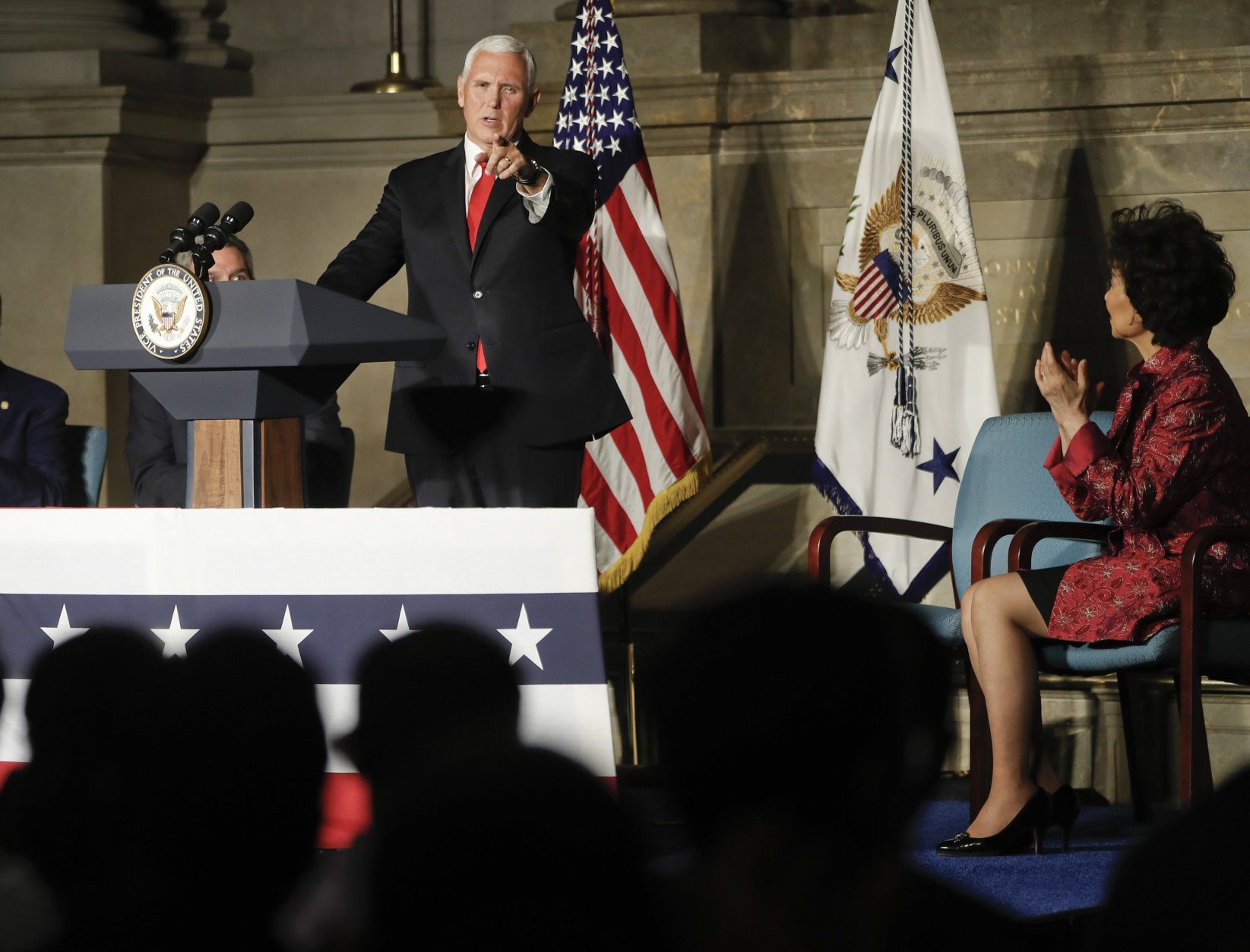 Vice President Mike Pence, points to new naturalized citizens while speaking at a naturalization ceremony in celebration of Independence Day at the National Archives in Washington, Thursday, July 4, 2019. Also on stage is Secretary of Transportation Elaine Chao, right seated. (AP Photo/Pablo Martinez Monsivais)