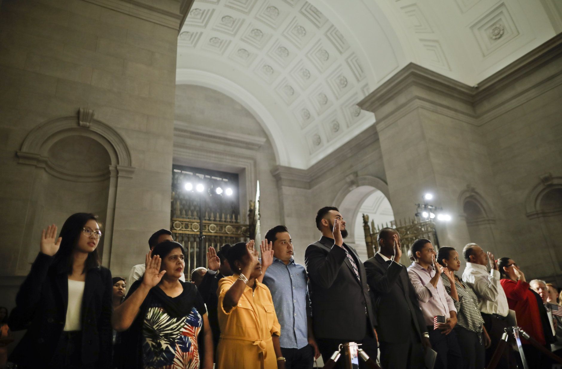 People raise their hands while taking the Oath of Allegiance during a naturalization ceremony in celebration of Independence Day at the National Archives in Washington, Thursday, July 4, 2019. (AP Photo/Pablo Martinez Monsivais)