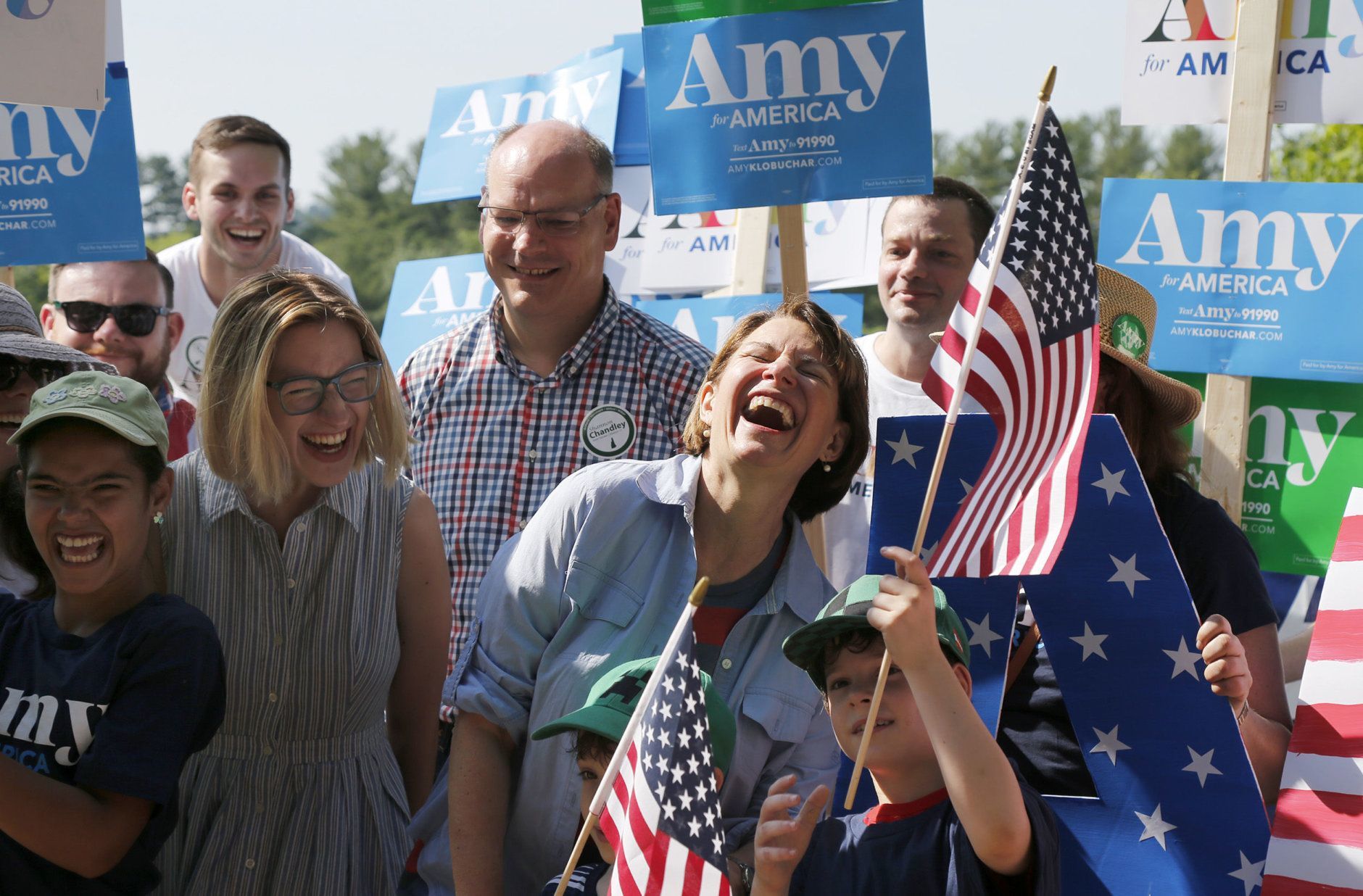 Democratic presidential candidate Sen. Amy Klobuchar, D-Minn., center, laughs with her husband John Bessler, and daughter Abigail Bessler, second from left, and as she greets her supporters during the Fourth of July Parade, Thursday, July 4, 2019, in Amherst. (AP Photo/Mary Schwalm)