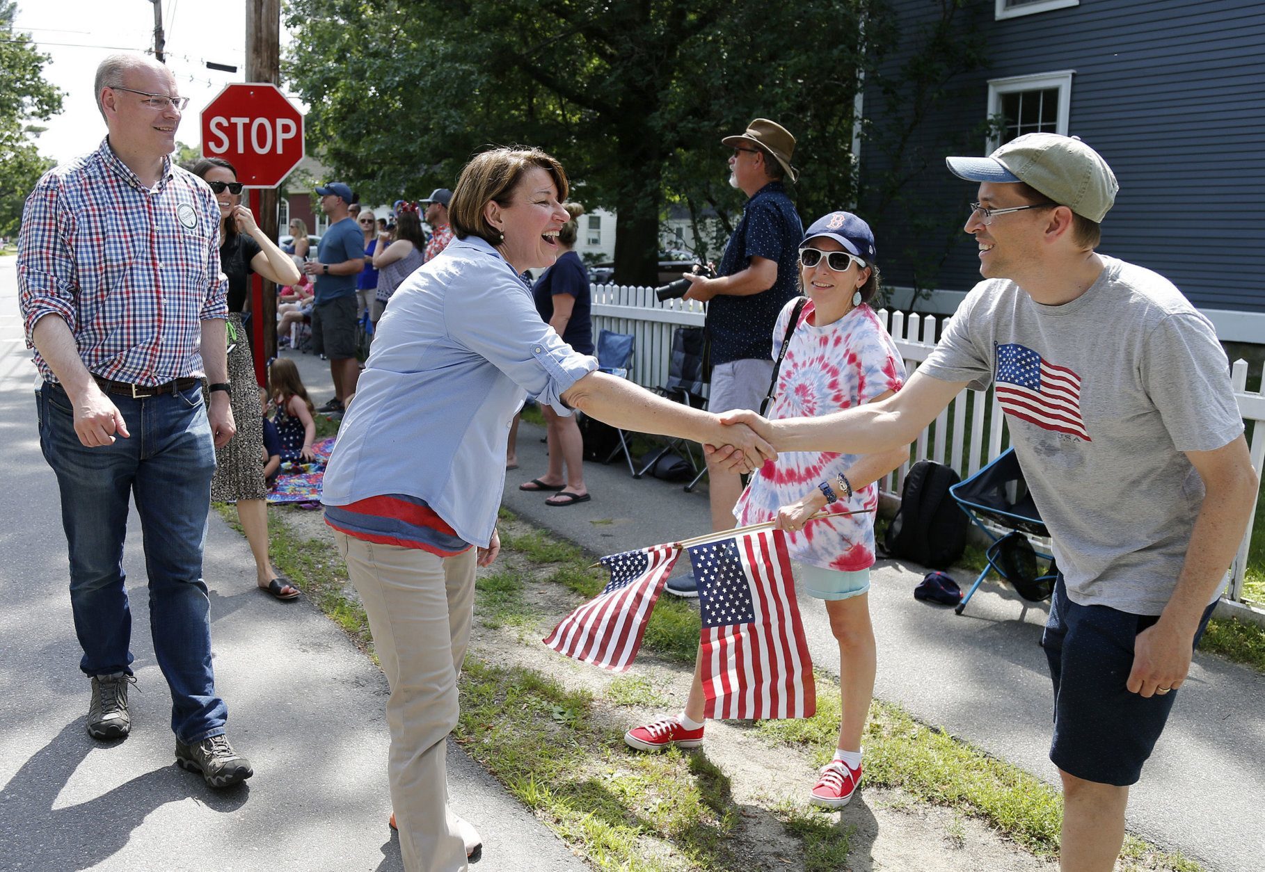 Democratic presidential candidate Sen. Amy Klobuchar, D-Minn., shakes hands with potential supporters along the route as her husband John Bessler looks on during the Fourth of July Parade, Thursday, July 4, 2019, in Amherst. (AP Photo/Mary Schwalm)