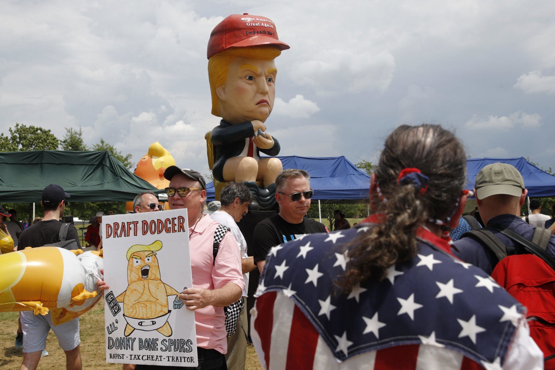 Protesters gather near a sculpture depicting President Donald Trump holding a cell phone on a toilet before Independence Day celebrations, Thursday, July 4, 2019, on the National Mall in Washington. (AP Photo/Patrick Semansky)