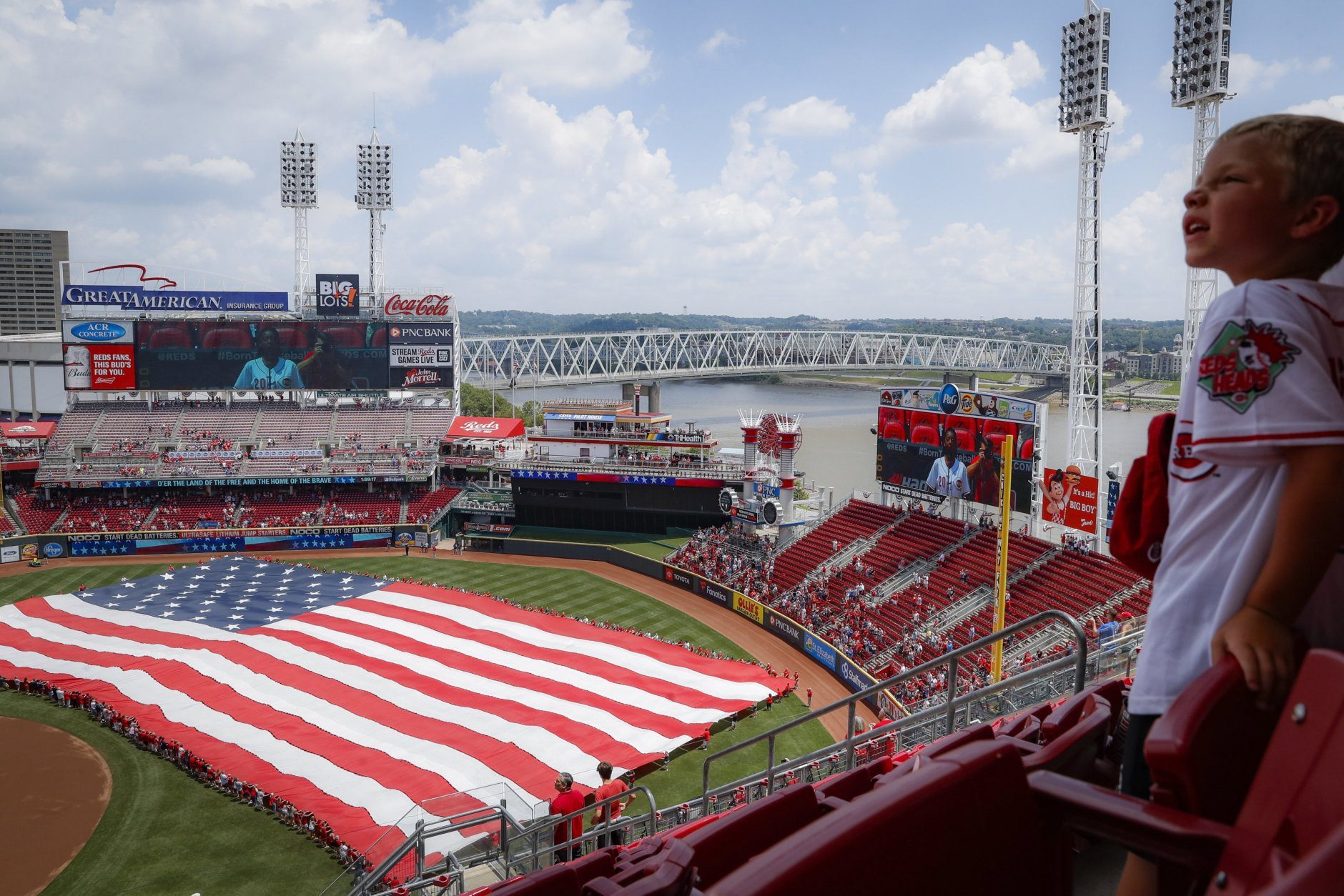 A giant United States flag is unfurled as the national anthem is played before a baseball game between the Cincinnati Reds and the Milwaukee Brewers, Thursday, July 4, 2019, in Cincinnati. (AP Photo/John Minchillo)