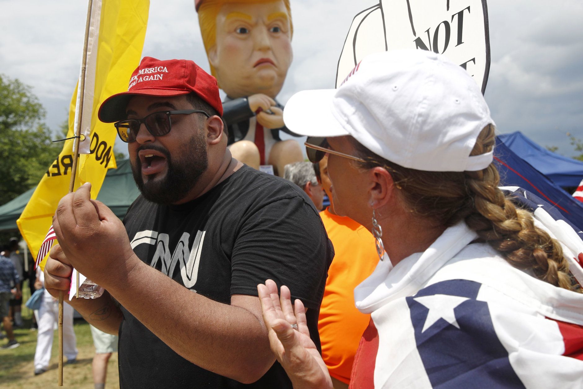 A supporter of President Donald Trump who gave his name as Moto Moto, left, of Brooklyn, N.Y., debates with protesters in front of a sculpture of President Trump holding a cell phone while sitting on a toilet before Independence Day celebrations, Thursday, July 4, 2019, on the National Mall in Washington. (AP Photo/Patrick Semansky)
