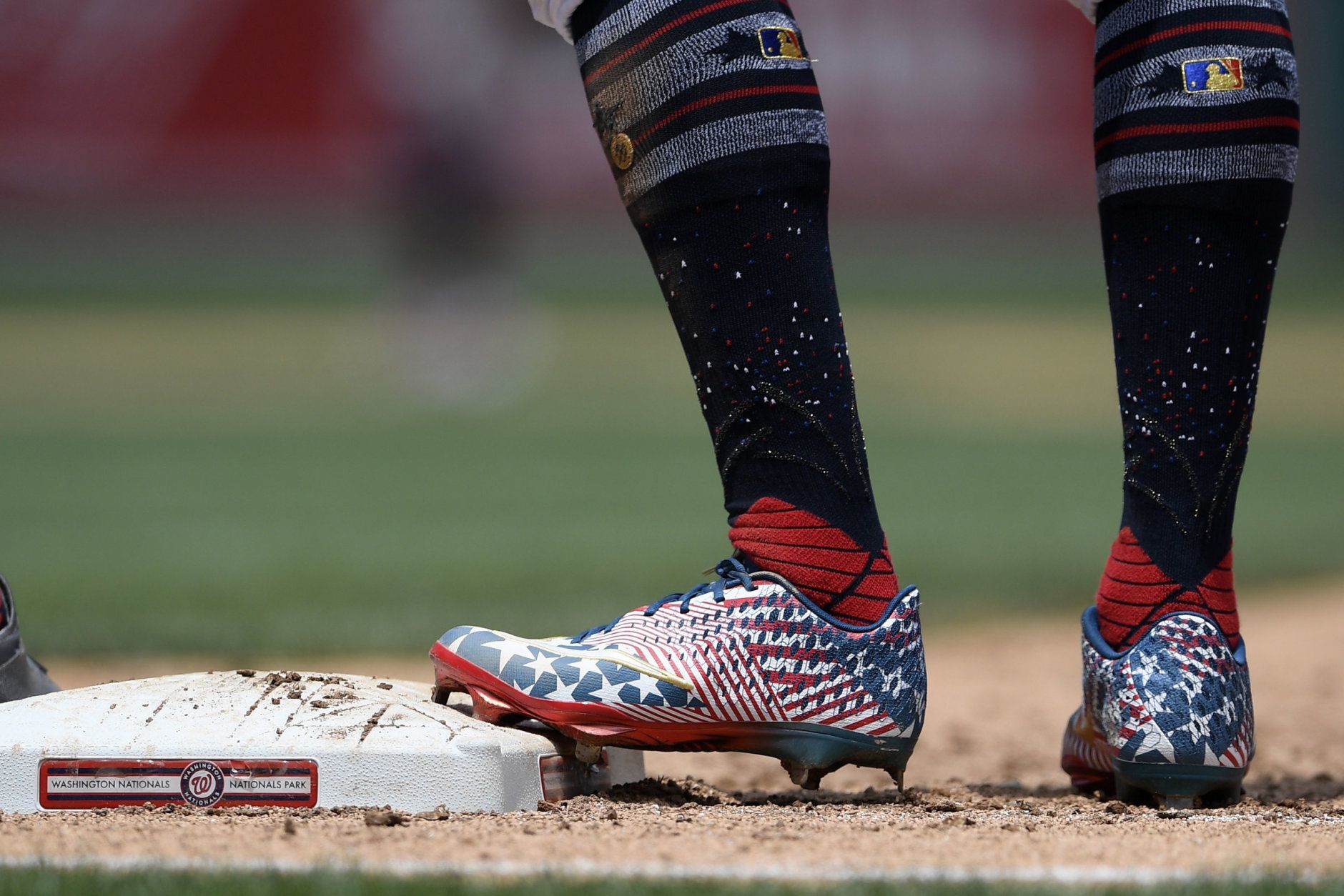 Washington Nationals' Victor Robles, right, stands on first wearing patriotic themed cleats during the sixth inning of a baseball game against the Miami Marlins, Thursday, July 4, 2019, in Washington. The Nationals won 5-2.(AP Photo/Nick Wass)