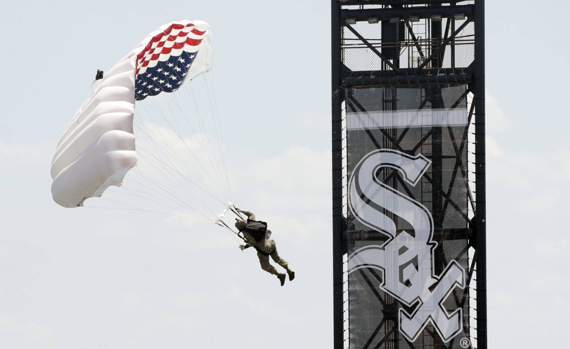 Frog-X parachute team member, retired U.S. Marine Marc Hogue glides toward the field before a baseball game between the Chicago White Sox and Detroit Tigers Thursday, July 4, 2019, in Chicago. (AP Photo/Mark Black)