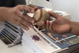 A Nats player autographs a baseball