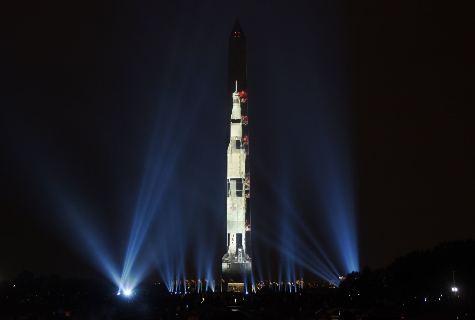 A projection of a 363-foot Saturn V rocket projected on the Washington Monument