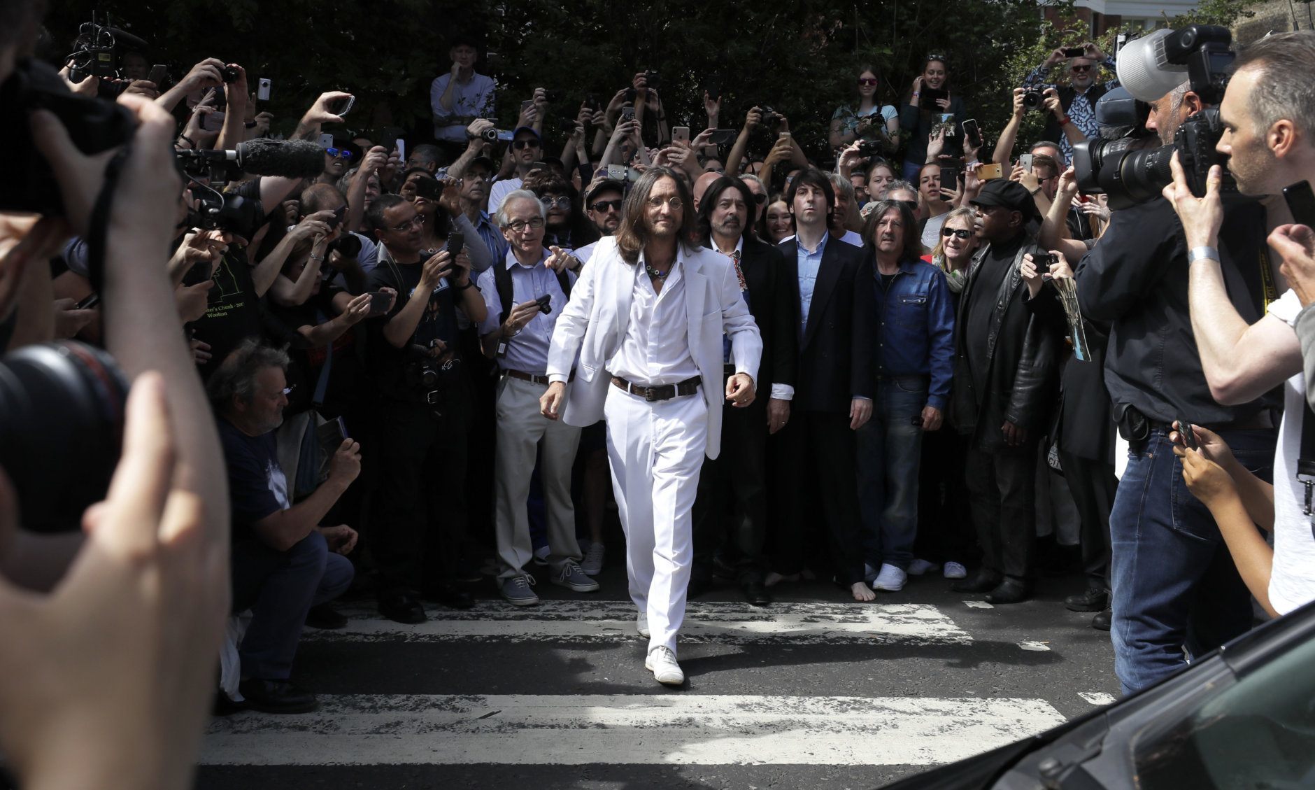 Thousands of fans gather to walk across the Abbey Road zebra crossing, on the 50th anniversary of British pop musicians The Beatles doing it for the cover of their album 'Abbey Road' in St Johns Wood in London, Thursday, Aug. 8, 2019. They aimed to cross 50 years to the minute since the 'Fab Four' were photographed for the album. (AP Photo/Kirsty Wigglesworth)