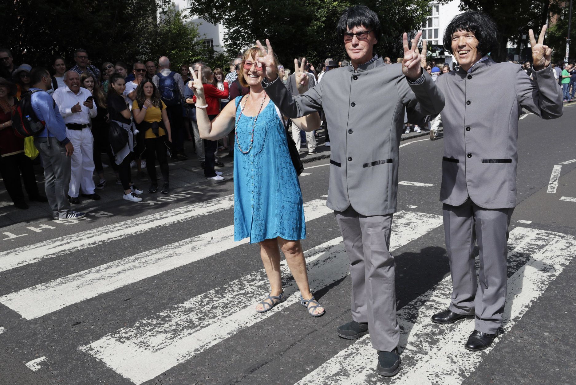Fans pose for a photograph as yhousands of fans gather to walk across the Abbey Road zebra crossing, on the 50th anniversary of British pop musicians The Beatles doing it for the cover of their album 'Abbey Road' in St Johns Wood in London, Thursday, Aug. 8, 2019. They aimed to cross 50 years to the minute since the 'Fab Four' were photographed for the album. (AP Photo/Kirsty Wigglesworth)