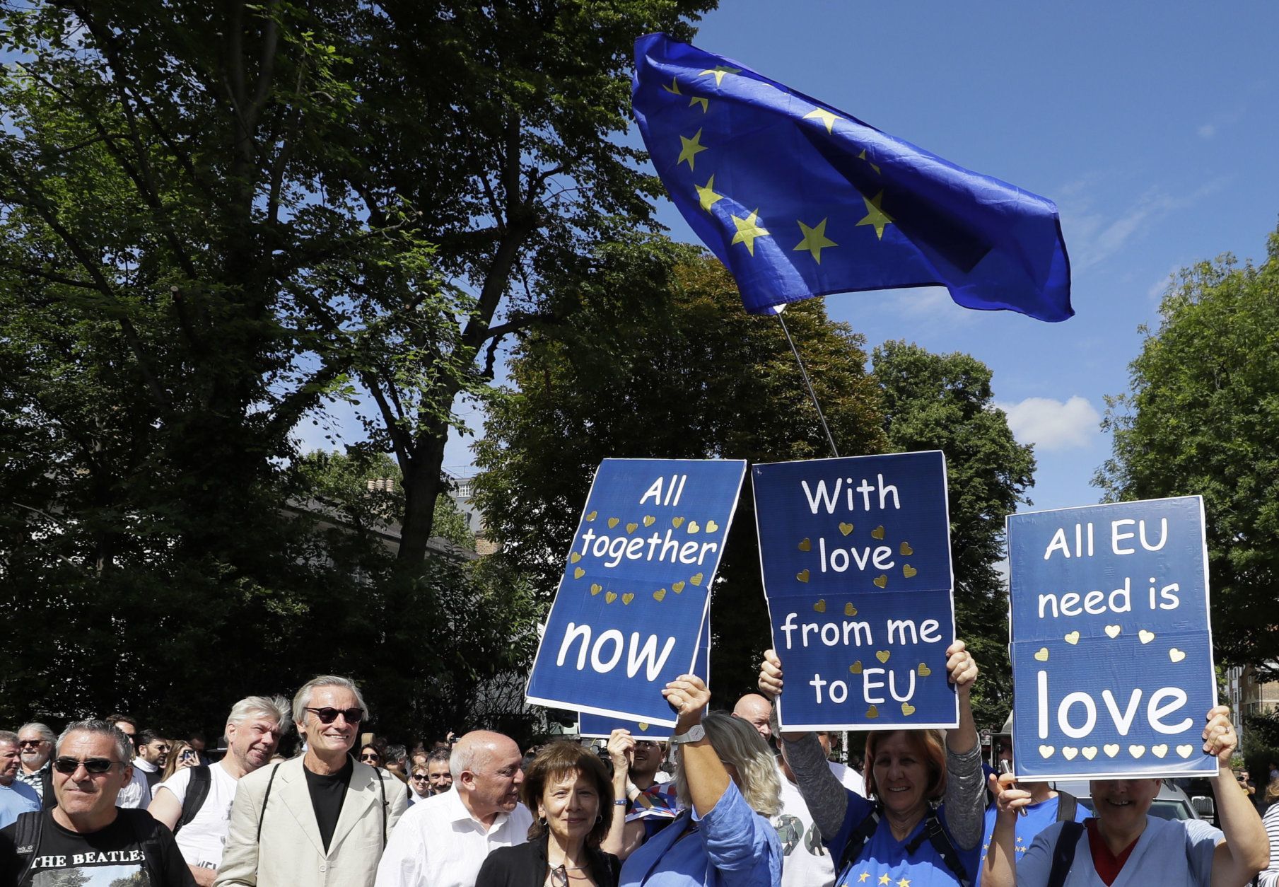 Anti Brexit demonstrators join Beatles fans, with signs reflecting Beatles songs, to walk across Abbey Road crossing on the 50th anniversary of British pop musicians The Beatles doing it, on Abbey Road in London, Thursday, Aug. 8, 2019. They aimed to cross 50 years to the minute since the 'Fab Four' were photographed for the Abbey Road album. (AP Photo/Kirsty Wigglesworth)