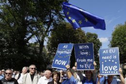 Anti Brexit demonstrators join Beatles fans, with signs reflecting Beatles songs, to walk across Abbey Road crossing on the 50th anniversary of British pop musicians The Beatles doing it, on Abbey Road in London, Thursday, Aug. 8, 2019. They aimed to cross 50 years to the minute since the 'Fab Four' were photographed for the Abbey Road album. (AP Photo/Kirsty Wigglesworth)