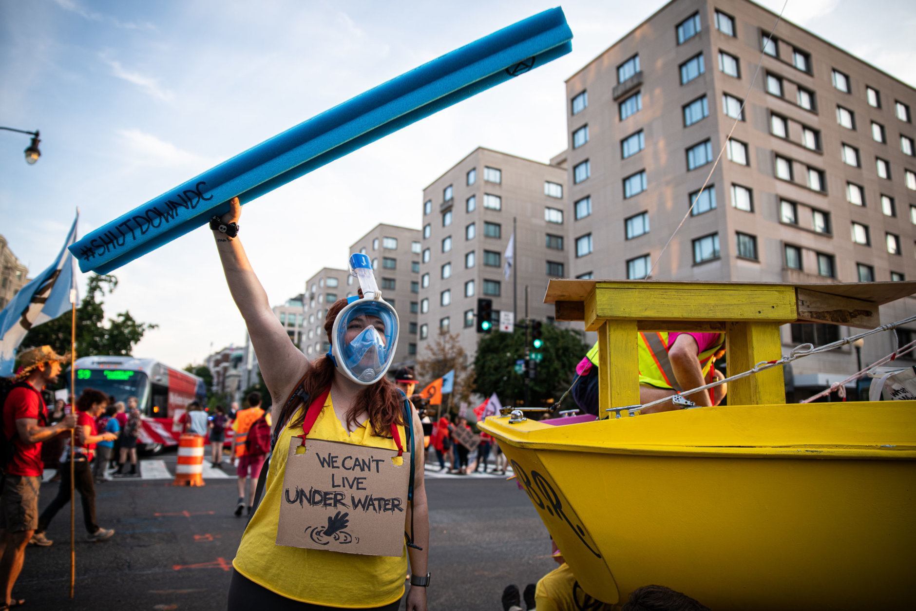 A protester with Extinction Rebellion wears a snorkel near a sailboat blocking the intersection of K and 16th streets in Washington, D.C. on Sept. 23, 2019. Environmental activists pressured lawmakers to declare a climate change emergency by paralyzing morning traffic in the nation's capital. (WTOP/Alejandro Alvarez)