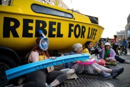 Protesters with Extinction Rebellion stage a sit-in beneath their sailboat blockade at the intersection of K and 16th streets in Washington, D.C. on Sept. 23, 2019. Environmental activists pressured lawmakers to declare a climate change emergency by paralyzing morning traffic in the nation's capital. (WTOP/Alejandro Alvarez)